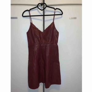  - Vinröd konstläders klänning i strl S. Aldrig använd och är ny.  Frakt tillkommer med 63 kr och samfraktar gärna. 