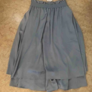  - Jättefin oanvänd kjol i ljusblå. Sitter tajt i midjan med resor men sedan sitter löst och fint! 