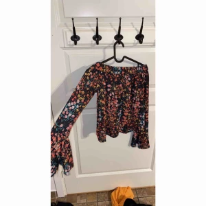  - Off shoulder topp med vida armar. Blommig. Aldrig använd. köparen står för eventuell frakt