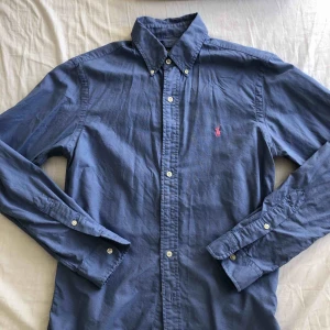  - Havsblå skjorta från Ralph Lauren med ett rosa polo märke. Storlek small slim fit