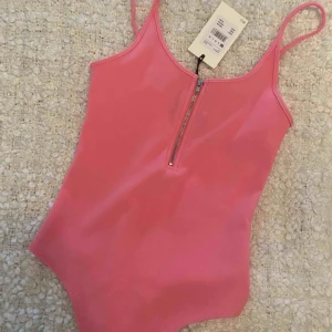  - Helt ny body med dragkedja i rosa från bik bok i storlek xs. Knäppning i grenen.  Prislapp kvar.