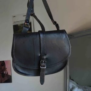  - Söt liten axelväska! Den va tidigare orange brun (se i väskan bild 3) men har sprejat den svart, där av ”dropparna” på framsidan. Inget jag har lagt märke till om man inte står med den i direkt solljus❣️  Frakt ingår i priset!