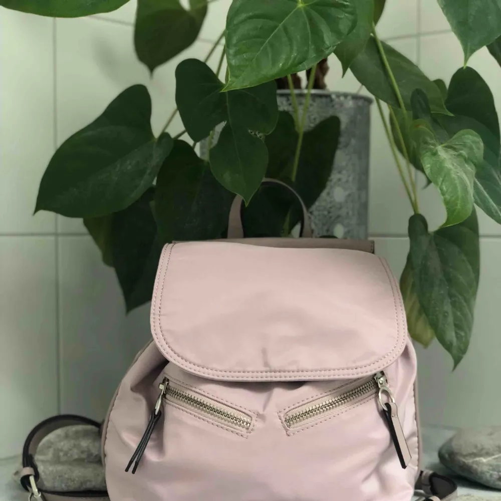 En skitsnygg pastellrosa ryggsäck från Parfois med många smarta fack och fickor. Får plats med mycket men ändå en liten väska. . Väskor.