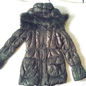  - Dunjacka perfekt till vintern med pälskrage på luvan, brun färg och slutar en bit ovanför rumpan. Varm och gosig, i jättebra skick och bra pris. Den enda som saknas är bältet. 