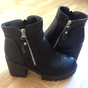  - Ett par skitsnygga chunky heels i svart fake-läder. Köpta på nätet men passade inte, pallade inte skicka tillbaka dom, därför säljer jag dom nu. Aldrig använda, bara testade inomhus. Skulle säga att dom är mer som 38or i storleken. Silver & svarta dragkedjor och stort mönsterdjup under sulan som kommer göra dig till en 100% kicker i höst & vinter! 
