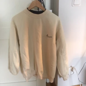  - Vitaktig tjocktröja med Nikelogga på bröstet. 