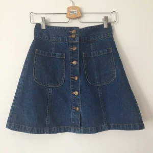  - Hög midja, mörkblå jeanskjol med framfickor och knappar