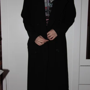 Trenchcoat  - En svart lång trenchcoat i storlek 38. Säljer pga för stor för mig. Den är jätteskön och väldigt snygg när den sitter bra. Inga slitningar och använt den ca 5 ggr! Köparen står för frakten 