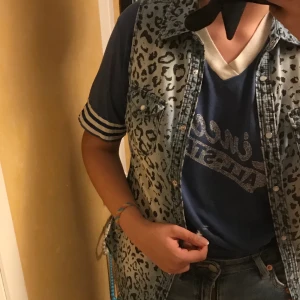 Fuskjean ärmlös kjorta strl 36 - Blå faded armlös fusk-jean kjorta, storlek 36 med leopardmönster och mjölkvita knappar. Passar ensam eller med andra toppar 💙 (frakt ingår ej)