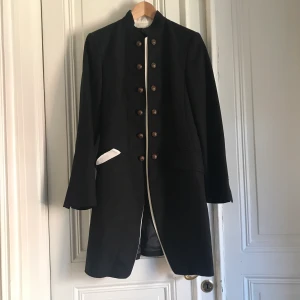 Zara kappa - Zara kappa. Svart/vit i seargent pepper stil. Slutar precis ovanför knäna. Passar storlek 38-40.