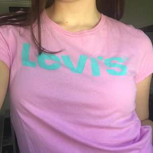 En T-shirt från Levis som är ljusrosa och pastell blå i storlek S. 