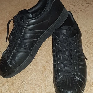 Helsvarta adidasskor  - Använda innomus några ggr men ser nästan oanvända ut, förurom att styngnen längst fram har släppt lite på ena skon (kolla bild 3) men det är inget man tänker på. kan mötas upp i sthlm annars trår köparen för frakt🥰 pris kan diskuteras