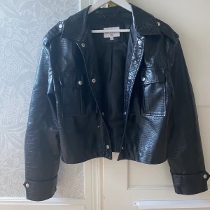 Skinnjacka i krokodilimitation - Super snygg jacka från NAKD i strl 38 den är lite oversized💗 jag är 168cm lång och har strl S/M i jackor, har använt jackan Max 5ggr då den har lite skav på nåra av dom silvriga knapparna på bröstfickan, inget jag sett förens nu när jag kollade noggrant på den! Köpte jackan för 700kr, (mitt pris 280)Skriv vid intresse eller om du har någon fråga. Köparen står för frakten (60kr)💗