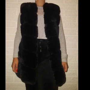 Svart Pälsväst - En fin pälsväst (inte äkta päls) i fint skick andvände fåtal gånger. Den här även fickor och spännen för att stänga den, (priset kan diskuteras de bara o skriva). jag är 158, har köpt den för 1,200kr