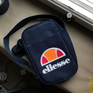 Elesse Väska - Liten crossbody väska / pouch bag i mörkblått från Elesse. Aldrig använd. 