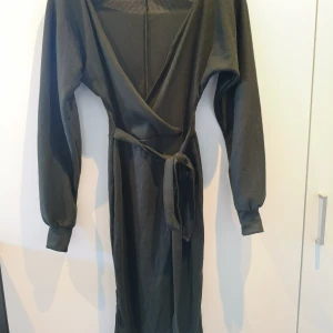 Ribbad klänning med slits från Boohoo - En lång mörkgrön klänning med slits på sidorna. Från Boohoo. Petite size i Storlek XS. Sitter tight och är i en slags omlottsmodell. Aldrig använd endast testad. 