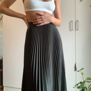 Mörkgrön midikjol - En mörkgrön plisserad midikjol som går ner över knäna i storlek 38. Resor i midjan, använd fåtal gånger. 