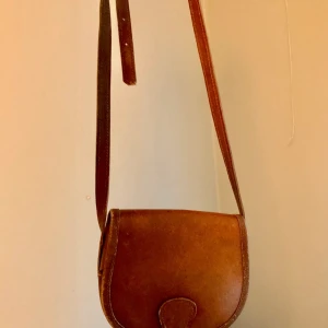 Söt handväska  - Snygg, brun och liten handväska i något skinn(?)material inköpt på någon second hand! Går att jusera bandet så den blir mycket längre om man vill :))