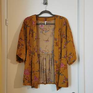 Senapsgul kort kimono med blommigt mönster från NLY trend. I strl 36 och true to size. 100% viskos. Använd ett fåtal gånger och i nyskick. 