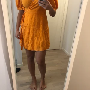 Orange klänning aldrig använd  - Jättefin orange kort klänning med puffärmar i linne tyg. Aldrig använd och köpt för 400 kr. Säljs för 50 kronor. 