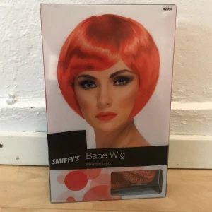 Oanvänd peruk - Röd korthårig peruk i sin förpackning. 