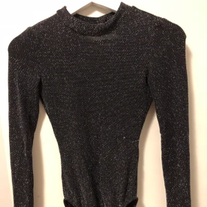  - Glittrig body med öppen rygg, storlek XS.