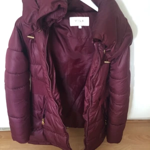  - Dunjacka i vinröd färg från Vila. Strl XS-S.