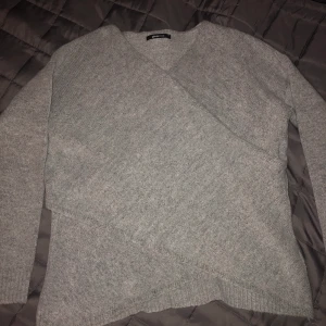 Stickad omlottröja - En fin ljusgrå stickad omlottröja i skönt material men som tyvärr inte kommer till användning längre... köparen står för frakten och det angivna fraktpriset kan ändras! 