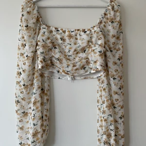 Kort blommig topp - En jättefin croppad blommig topp med ”genomskinligt” tyg på ärmarna. Använd 2 ggr och köpt på boohoo. Säljer för att jag inte är bekväm i så korta tröjor💕💖 