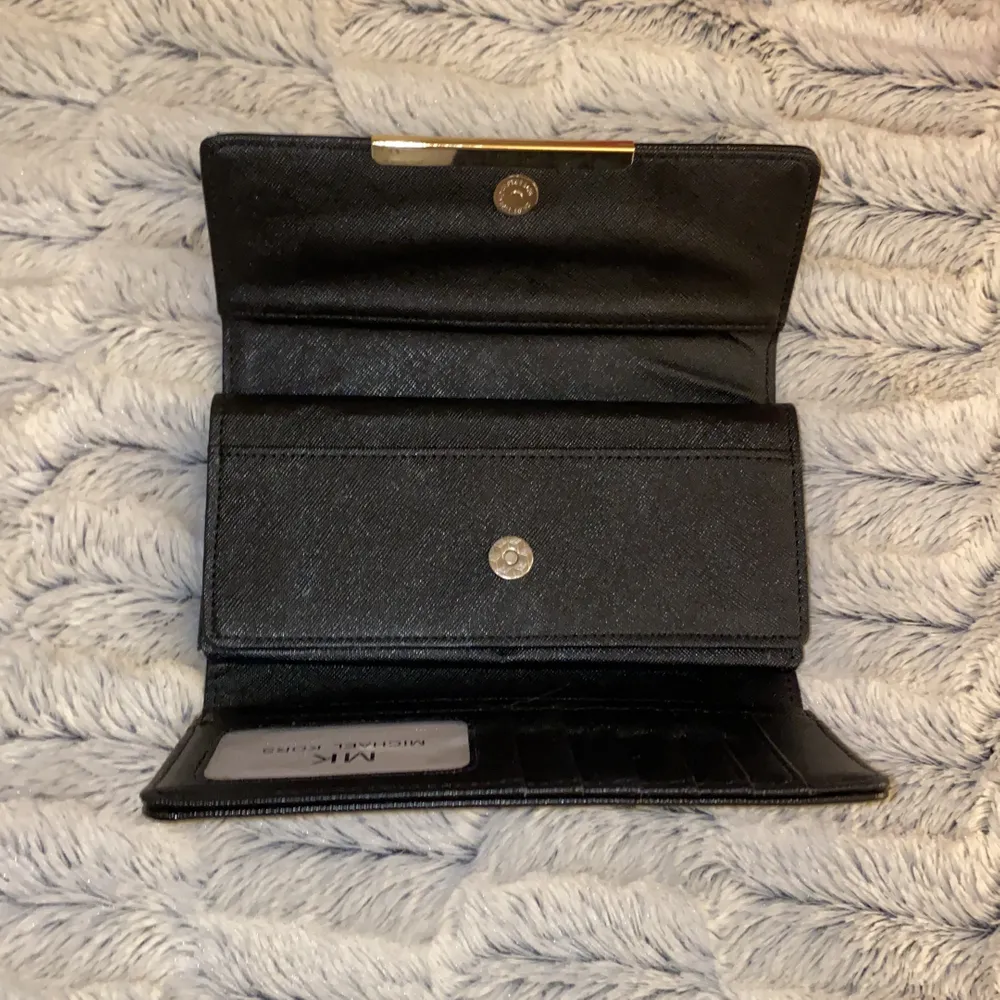 En skit snygg micheal kors plånbok i svart med guld. Vet inte om den är äkta eller inte då min mammas kompis köpte den som en present. . Väskor.