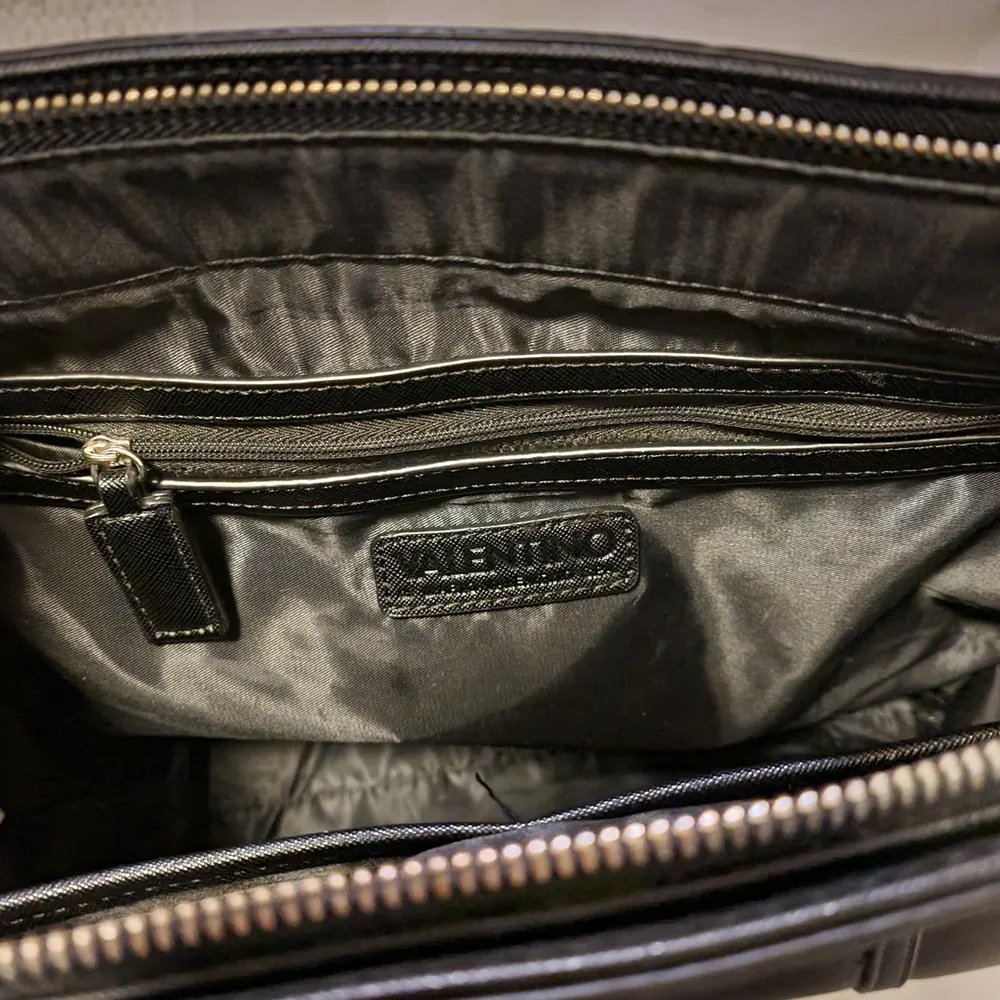 En svart Valentino handväska som har måttet 40x30cm. Nypris: 1250 kr. Den är lite sliten på något hörn, därav lågt pris. Det syns endast om man kollar noggrant. Frakt tillkommer. Betalning sker via swish:). Väskor.