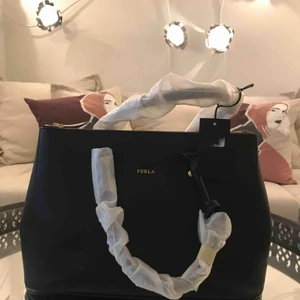  - En svart väska ifrån äkta Furla Dust bag och prislapp tillkommer! Kvitto finns ej kvar. Aldrig använd och handtagen är fortfarande inpackade.  Vid flera intressen, budgivning!