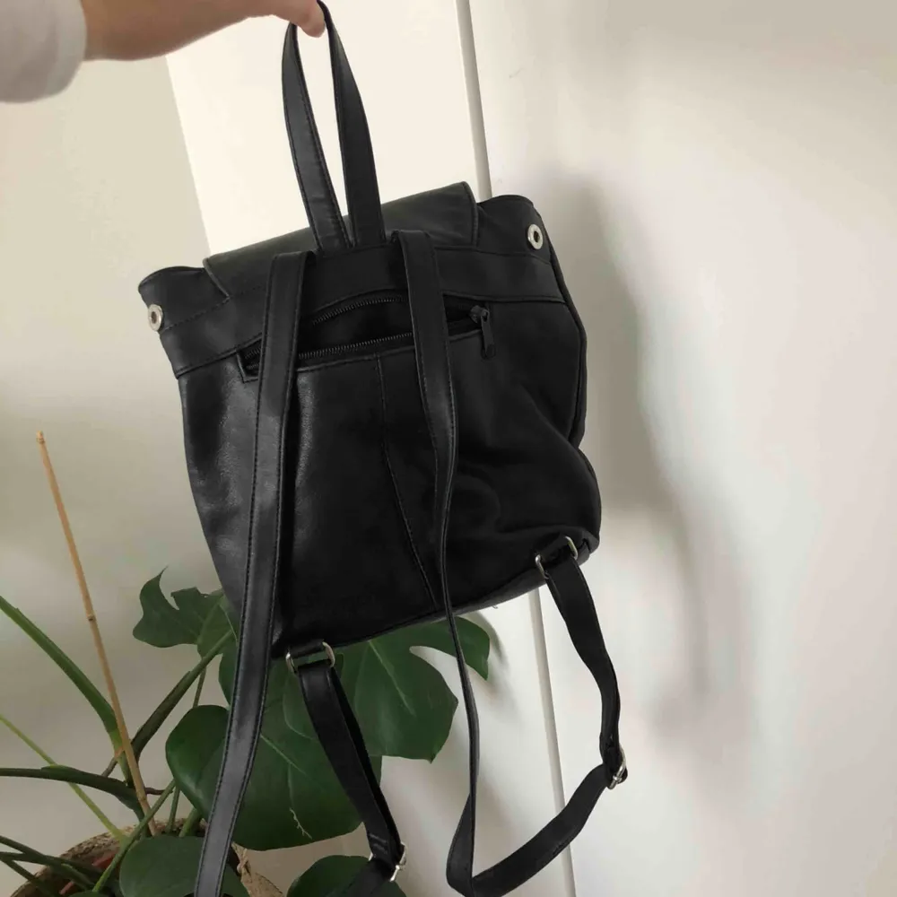 En svart liten väska med ytterfack och innerfack, i fint skick.  Spännbara band. . Väskor.