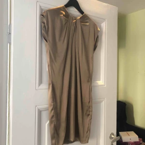  - Italiensk sidenklänning. 96%silk 4% elastan. Storleken är italiensk 40 vilket motsvarar S/36. Fråga om du önskar mer beskrivning. Använd 1 gång. Är härligt skimrande i färgen(guld/beige).