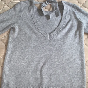 Grå stickad tröja från SALT - En super fin grå stickad tröja från SALT. Har används 2 gånger. Öppen i rygg där man själv kan justera med hjälp av snörena. Köparen står tyvärr för frakten💕