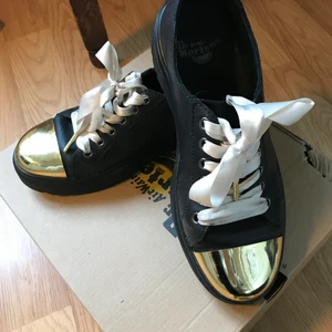 Dr Martens med silkesskosnören och förgylld tåhätta  - Har bytt ut originalskosnörena mot ljusrosa silkesband. Sköna, lätta lågskor (lite sneakerskänsla) med gulddetalj. Finns inte kvar på Dr Martens webshop. Välbehållna. 