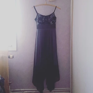  - Tjusig svepande klänning med ljuslila undertyg och svart, draperad mesh som ytterkjol samt svart spets i toppen. Använd en gång. Passar dig som gillar att verka mystisk.