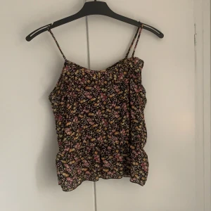 Blommig topp - Blommigt linne från bikbok. Tunt fint tyg, polyester. Säljer då den tyvärr har blivit lite för liten för mig. Fint skick! Har sytt upp banden, se bild 3, men går enkelt att ta upp om det önskas. Skriv om du vill se fler bilder!