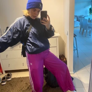 Rosa trackpants Adidas  - Säljer mina älskade trackpants från Adidas på grund av att dom inte riktigt passar mig storleksmässigt längre! Otroliga byxor!!! Använda några gånger, men i samma skick som vid köp!! Dom är i storlek M men skulle säga att dom passar både S/M beroende på hur du vill att dom ska sitta! Jag är en M/L så ni kan ju se hur dom sitter på mig! Köp så mina fina byxor så dom kan få ett nytt hem!!🥰🥰