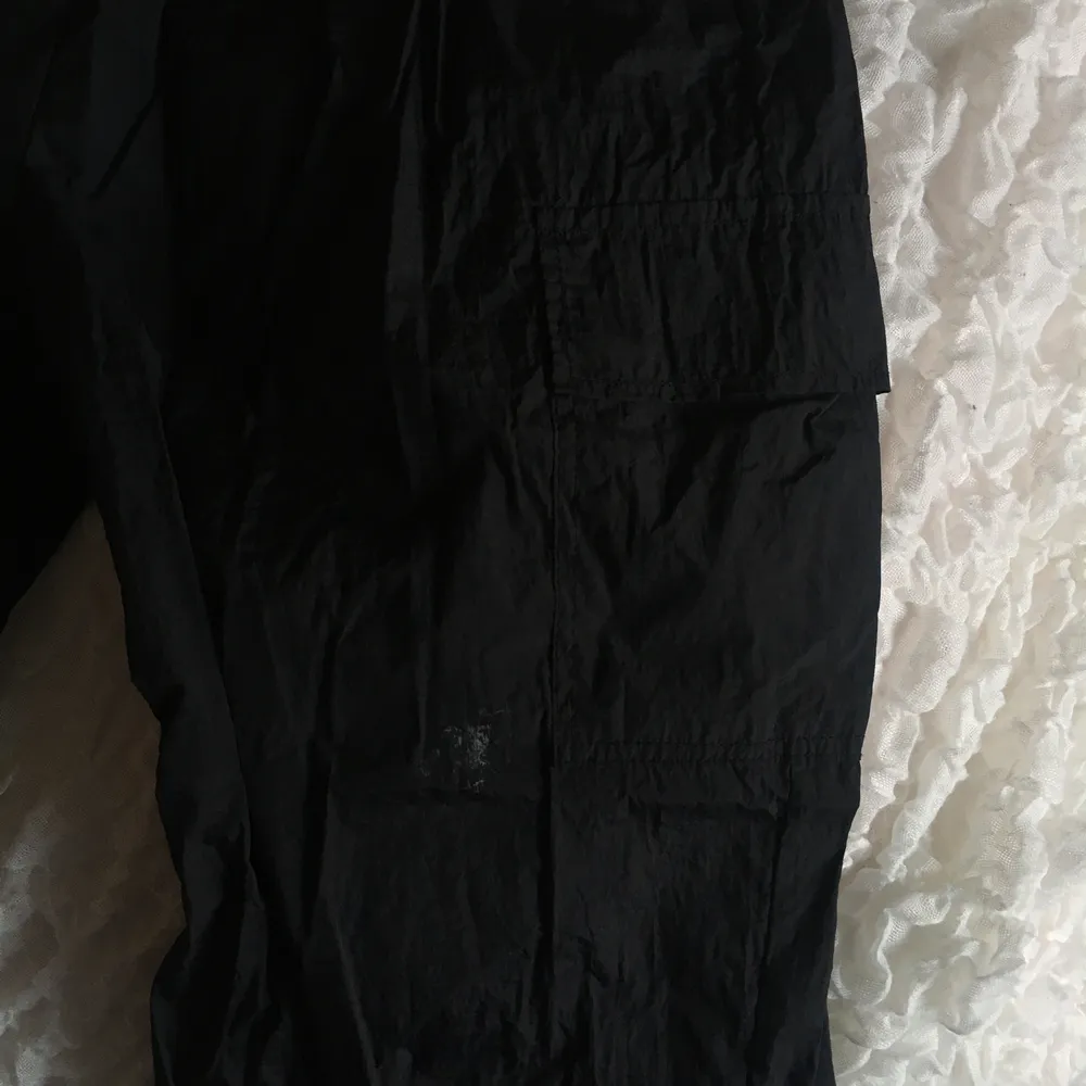 Såå snygga byxor i ”prassel material” från Asos!! Lite cargopants stil, svarta med fickor. Så fina! Och sitter skitsnyggt på! Har en liten vit fläck av något slag på ena benet (se bild 2+3), syns dock väldigt lite och går nog att få bort med nåt medel! ✨🤍🌻. Jeans & Byxor.