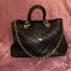 Svart handväska i läder ✨ - En svart handväska i äkta svart läder, med ett avtagbart axelband. Fina guld detaljer, två stora och små fack inuti. Brunt tyg på insidan. Väldigt bra skick med få repor. Väskan är från mitten av 2000-talet. ✨