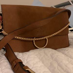 Mockaliknande brun väska från Forever 21, använd fåtal gånger i väldigt fint skick! Guldiga detaljer och justerbart band som även går o göra kortare/längre. 