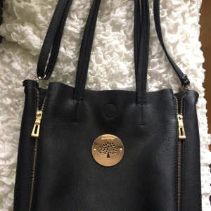  - Rymlig väska som är mur-berry inspirerad  Knapp med magnet, band till axeln  Läderimitation 