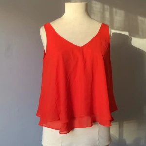  - Röd top med dubbla volanger och V-ringning, passar somriga dagar. Nästan helt oanvänd!   Frakt ingår ej, kan mötas upp i Stockholm.