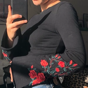 Svart tröja med brodyr - Långärmad tröja från Urban Outfiters med supersnygg brodyr på ärmarna. Passar s/xs