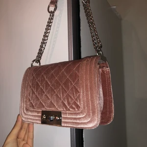 Sammet väska från gina tricot - En rosa axelbandsväska i sammet med silverdetaljer, köpt från gina tricot. Bandet går att justera ifall man vill ha den kort eller vill ha den längre runt sig. Den är använd mycket och det förekommer små fel dock inget som är märkvärdigt.  