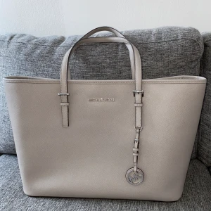 Äkta Michael Kors väska  - Oanvänd Michael kors väska. Har bara stått i garderoben så dags att sälja. Kvitto finns. Nypris: ca 2600kr. Mycket fack i väskan. Prislapp sitter kvar.