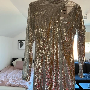 Festklänning - Oanvänd silvrig paljettklänning från Linn Ahlborgs kollektion med Na-kd! Har en bra passform och en snygg cutout vid nyckelbenet och som är lite högre i halsen! Ord pris 359kr, köparen står för frakt