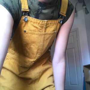 Hängselbyxor - Superfina Gul/orangea hängselbyxor från monki. Dom är i gott skick och har bara andvänts ett fåtal gånger. Dom är i jeansmaterial och går ända ner till fötterna på mig som är ca 176cm. Fraktar eller möts på Södermalm. 100kr+ ev frakt.