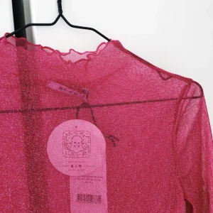  - Glittrig tröja från NA-KD i rosa typ mesh-tyg, Helt oanvänd med prislappar och tags kvar. Storlek M men passar S också då den är väldigt liten och stretchig. Köpare betalar frakt :)